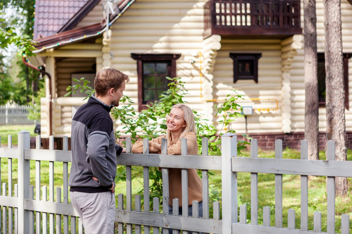 Neighbors talking over a fence.