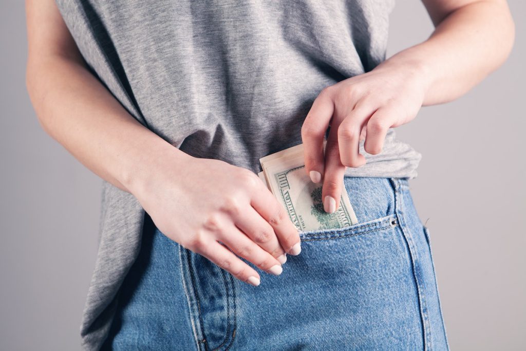 Woman putting money inter her pocket because she saved money on moving costs